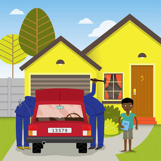 A boy holding a book and two men working on a car.