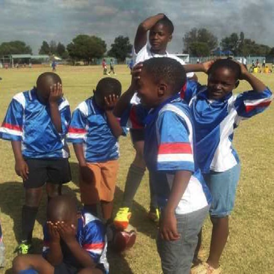 A soccer coach and boys in soccer shirts looking upset.