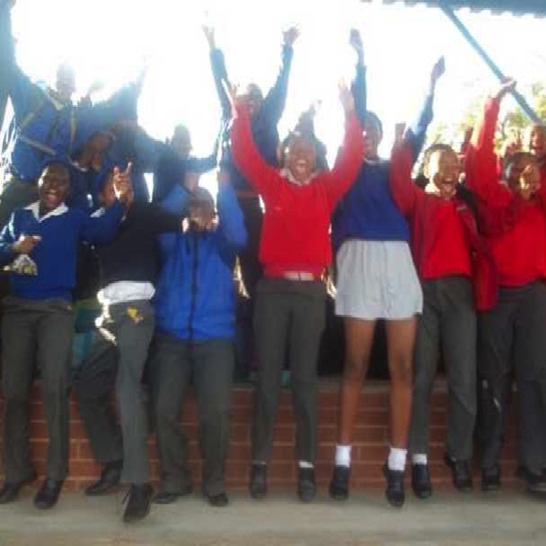 Girls and boys cheering with their arms in the air.